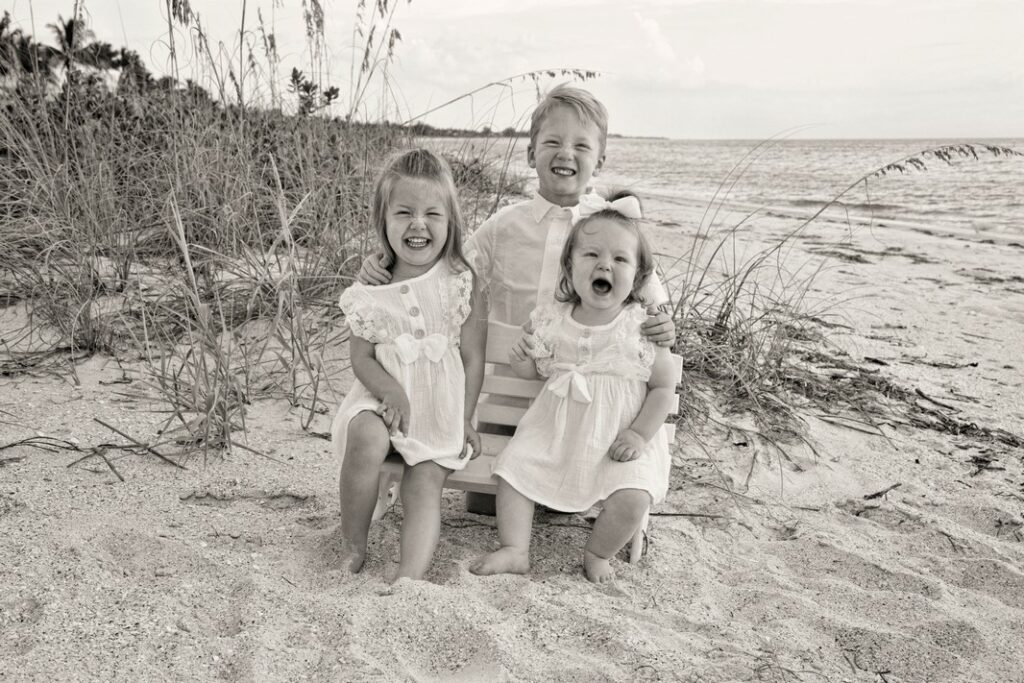 black and white beach portrait of three little children giggling