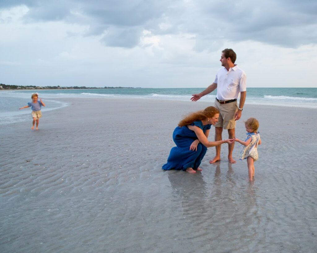 child running to her parents and brother along the shore in Boca Grande, FL