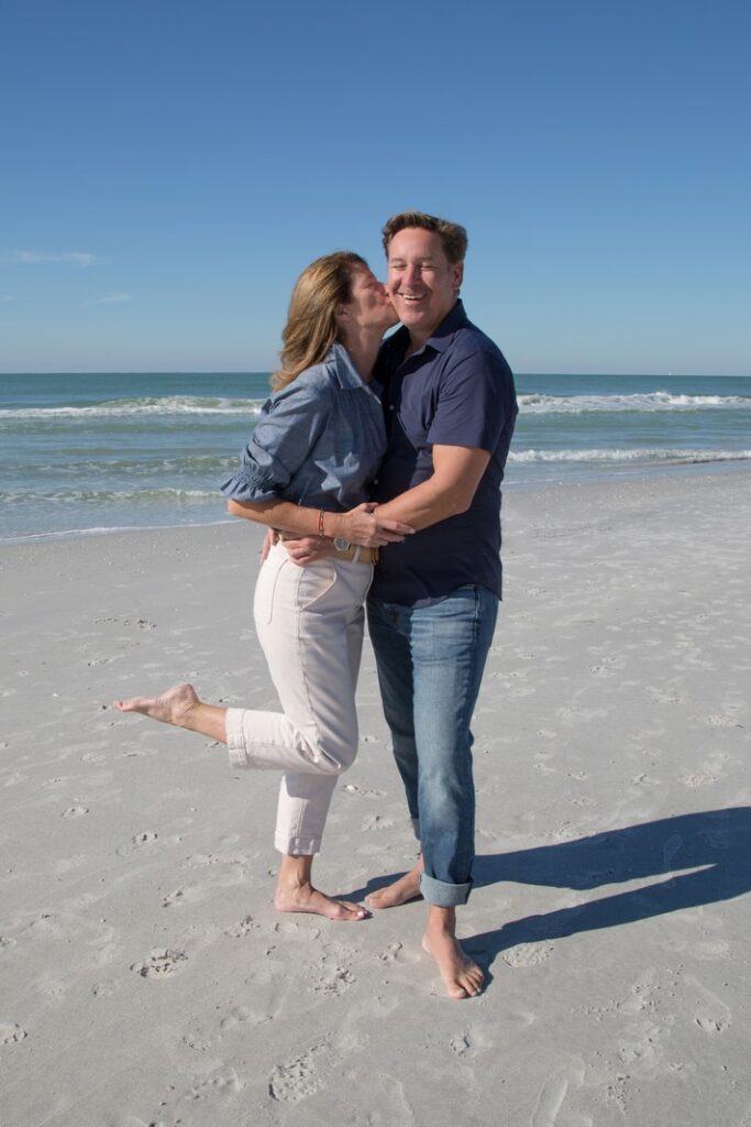 wife kisses husband's cheek in a romantic portrait on the beach in Boca Grande, FL