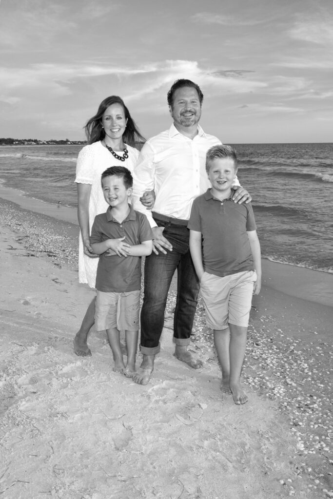 black and white portrait of a family of four on the beach