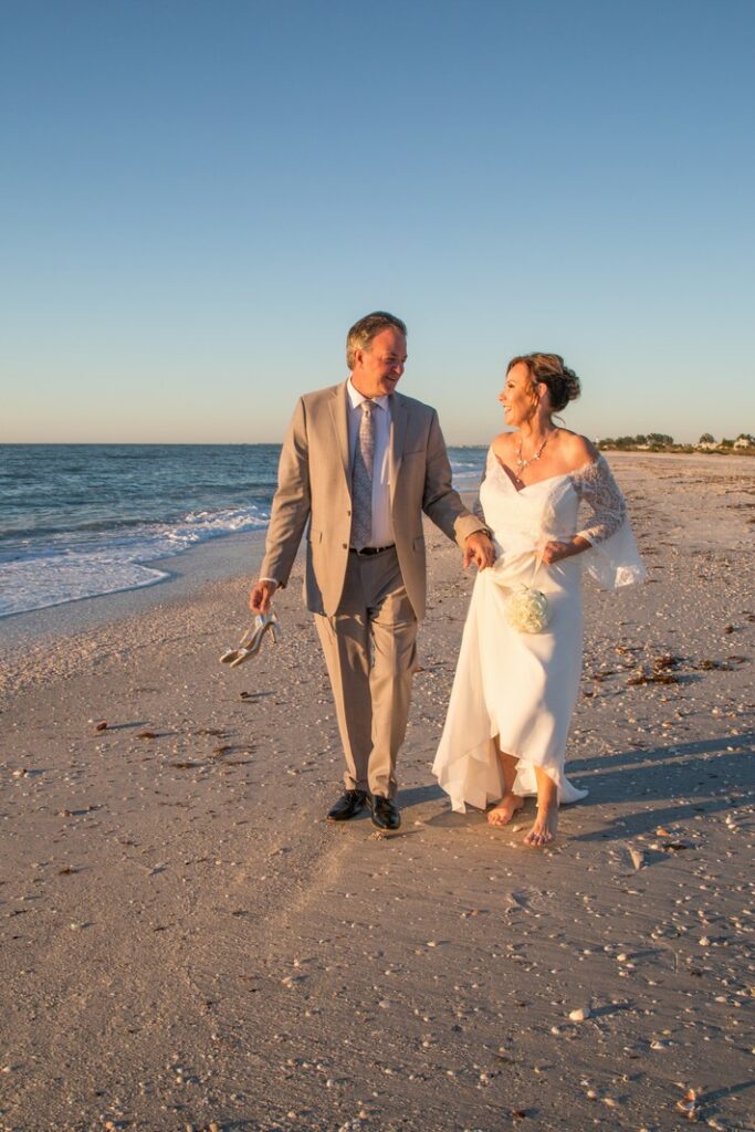portrait of middle aged bride and groom walking on the beach