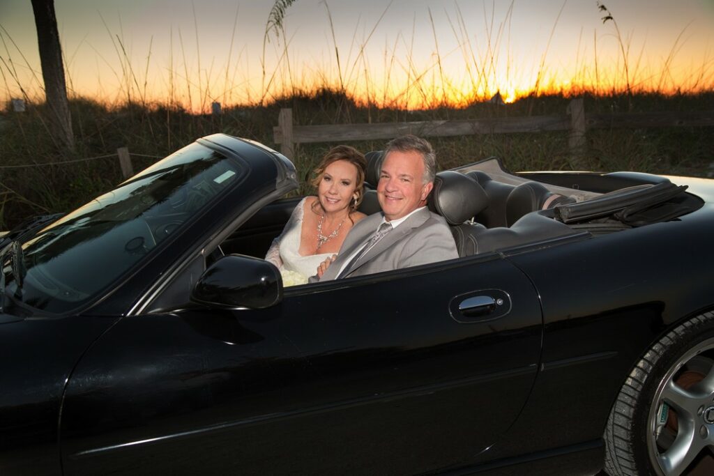 middle aged bride and groom in a black convertible at sunset near the beach in Boca Grande, FL