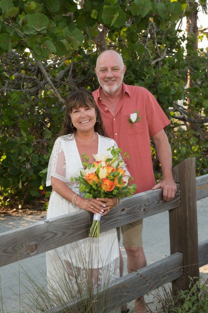 bride holding yellow and orange flowers and groom wearing a salmon colored shirt