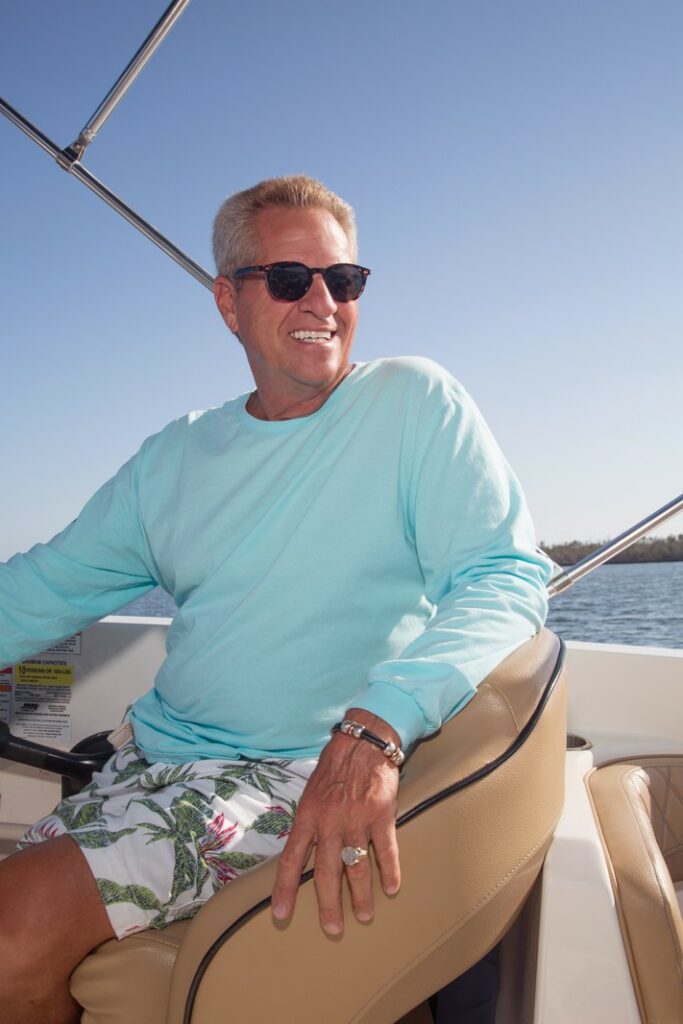 business portrait of a man driving a boat, wearing a blue shirt and sunglasses